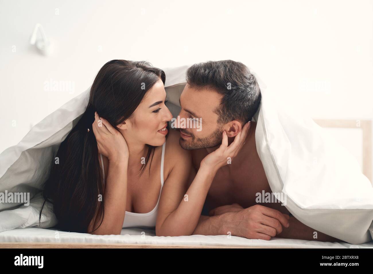 Happy married couple lying under the blanket Stock Photo