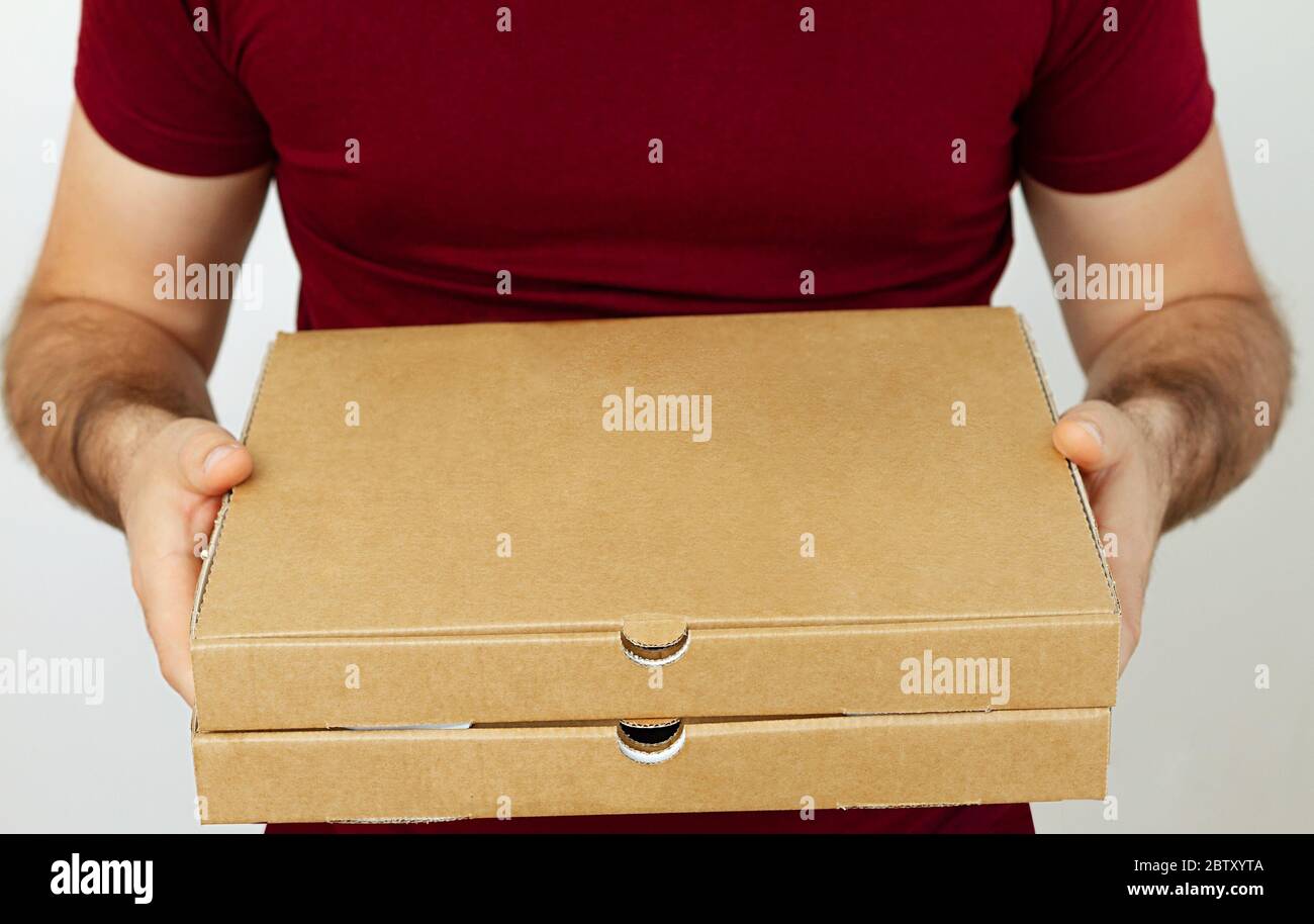 Delivery man in red t-short holding cardboard boxes of pizza on white background. Pizza delivery. Courier home delivery. food order pizza boxes Stock Photo