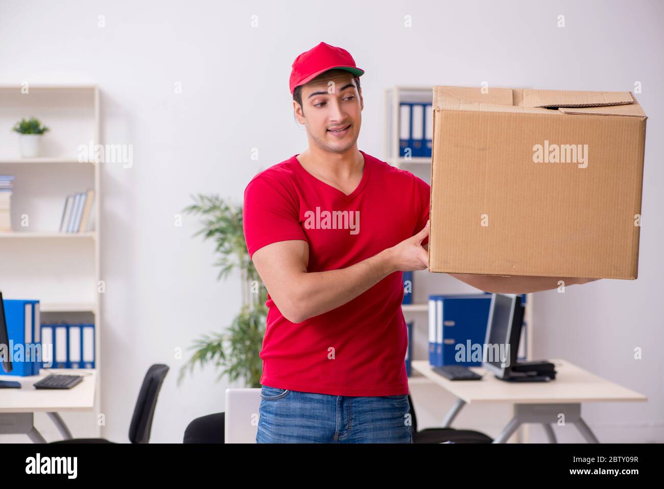 Young courier delivering postbox to the office Stock Photo Alamy