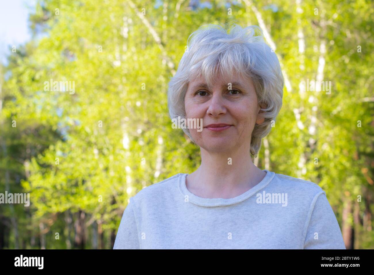Portrait of a happy middle-aged woman walking in the park. Bright sunny day. Good mood. Space for text. Stock Photo