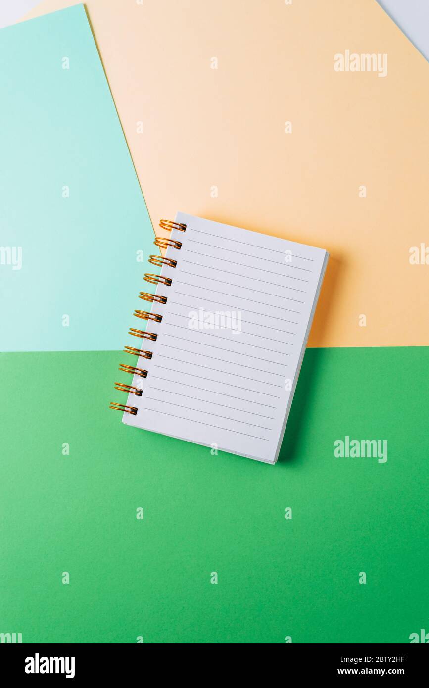 notebook with blank sheet and golden spiral on a colorful pastel background. Stock Photo