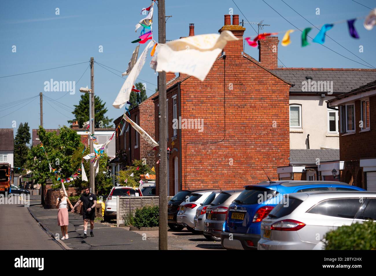 Duncombe Street in Wollaston, where artist Luke Perry has hung bunting with messages of support for neighbours and key workers, to create a 500 metre corridor of colour through the West Midlands village. Mr Perry asked local residents and shopkeepers to submit designs and messages, which he then hand painted and stitched onto bunting with the help of volunteers. Stock Photo