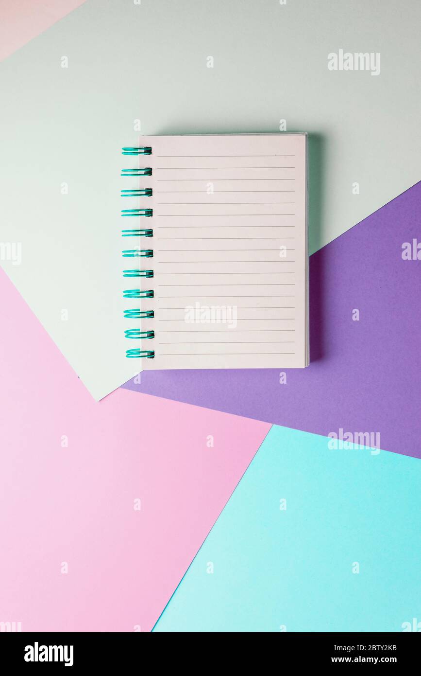 notebook with blank sheet and blue spiral on a colorful pastel background. Stock Photo