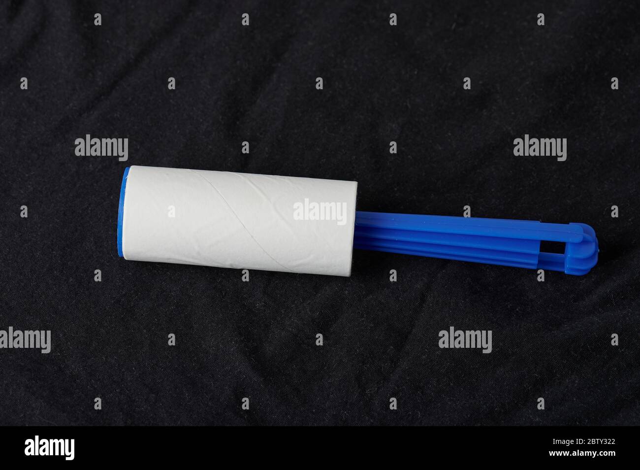 Sticky roller tool on black fabric material background Stock Photo