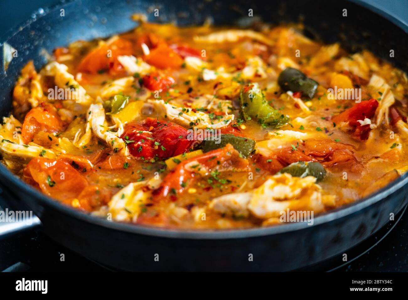 Chicken ragout with tomatoes, pepper and onion in cooking pan Stock Photo