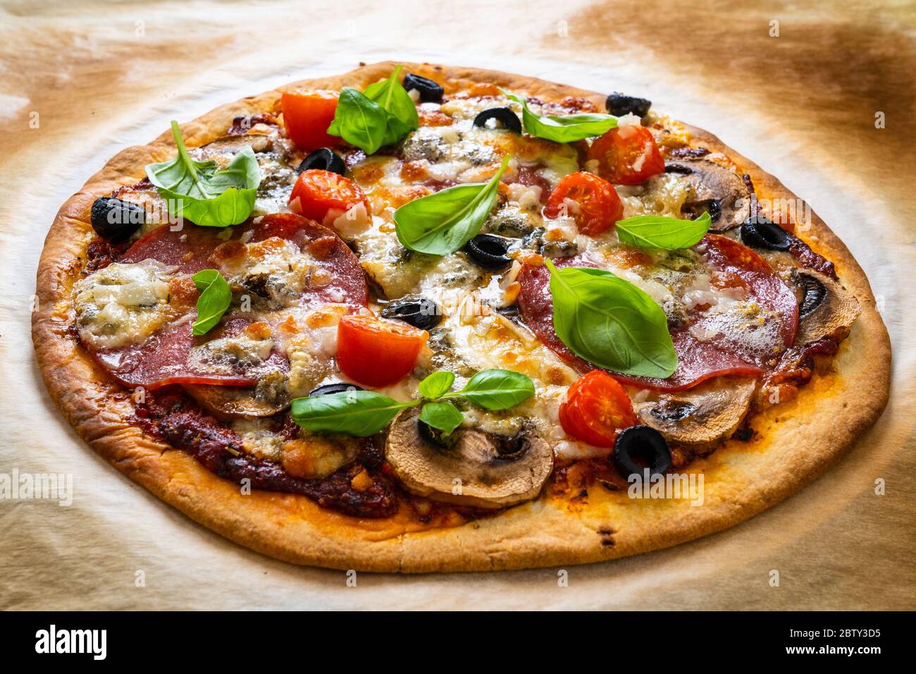Pepperoni pizza with salami, olives, cherry tomatoes and basil Stock Photo