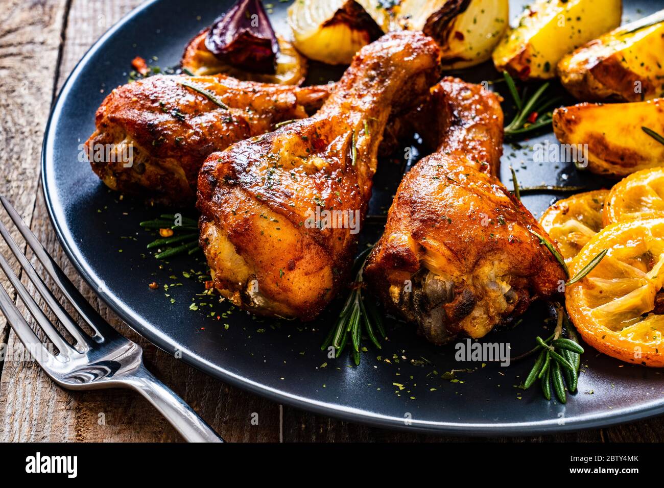 Grilled chicken drumsticks with baked potatoes and onions Stock Photo