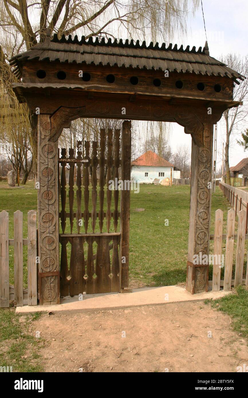 Covasna County, Romania. Traditional wooden gate decorated by local artisan with intricate carvings. Pigeonholes under the gate's roof. Stock Photo