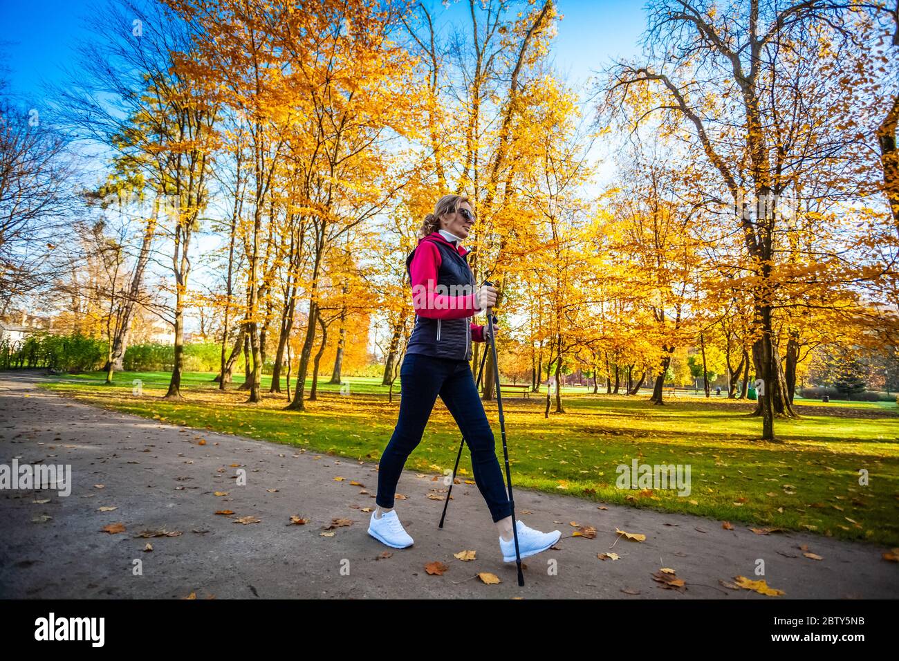 Nordic walking - middle-age woman working out in city park Stock Photo