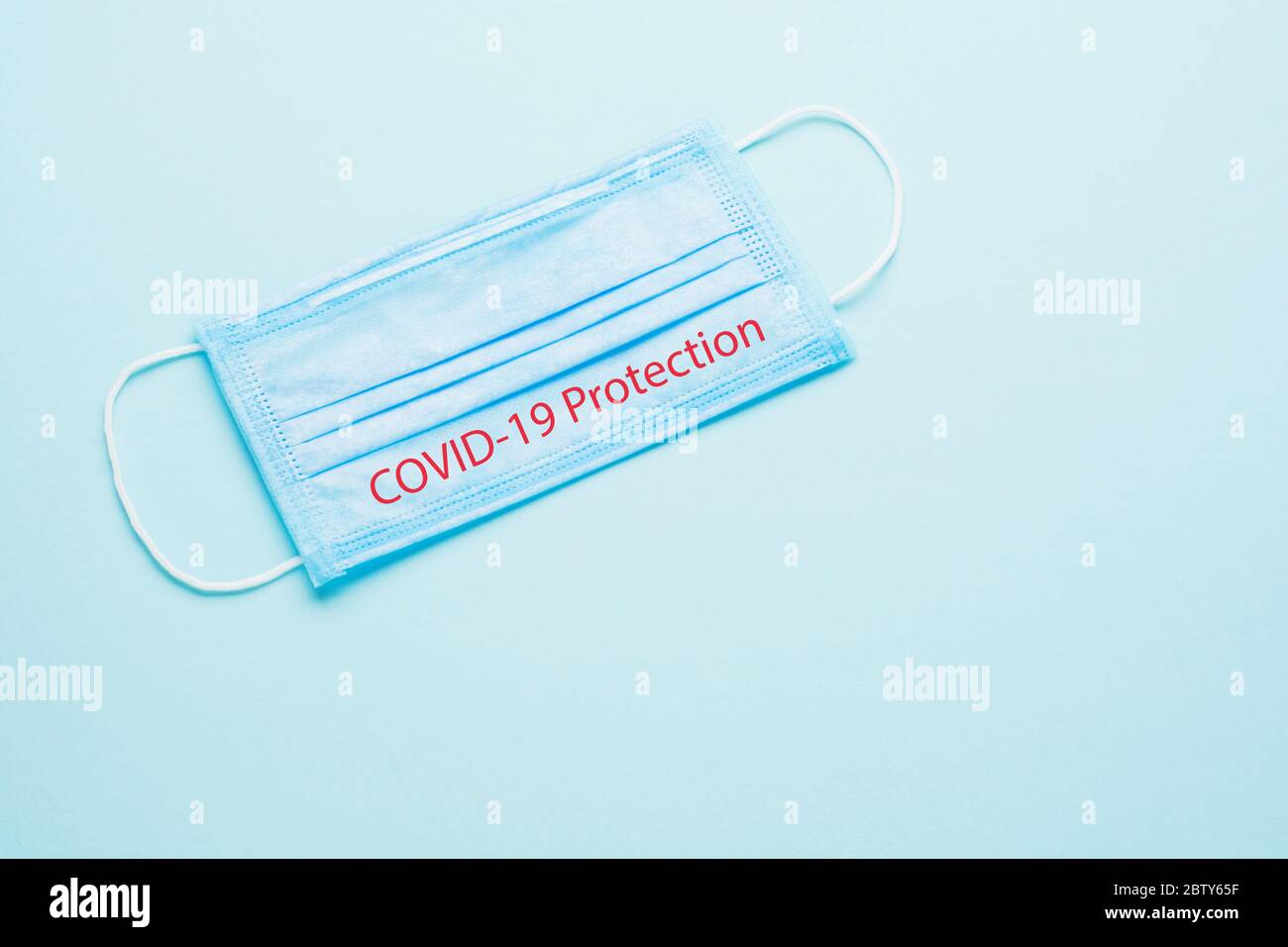 Blue Medical Disposable Face Mask with covid-19 printed on it. Coronavirus pneumonia gets official name from WHO: COVID-19. Disposable breath filter Stock Photo