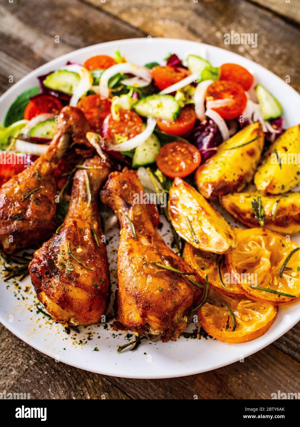 Grilled chicken drumsticks with baked potatoes and vegetables Stock Photo