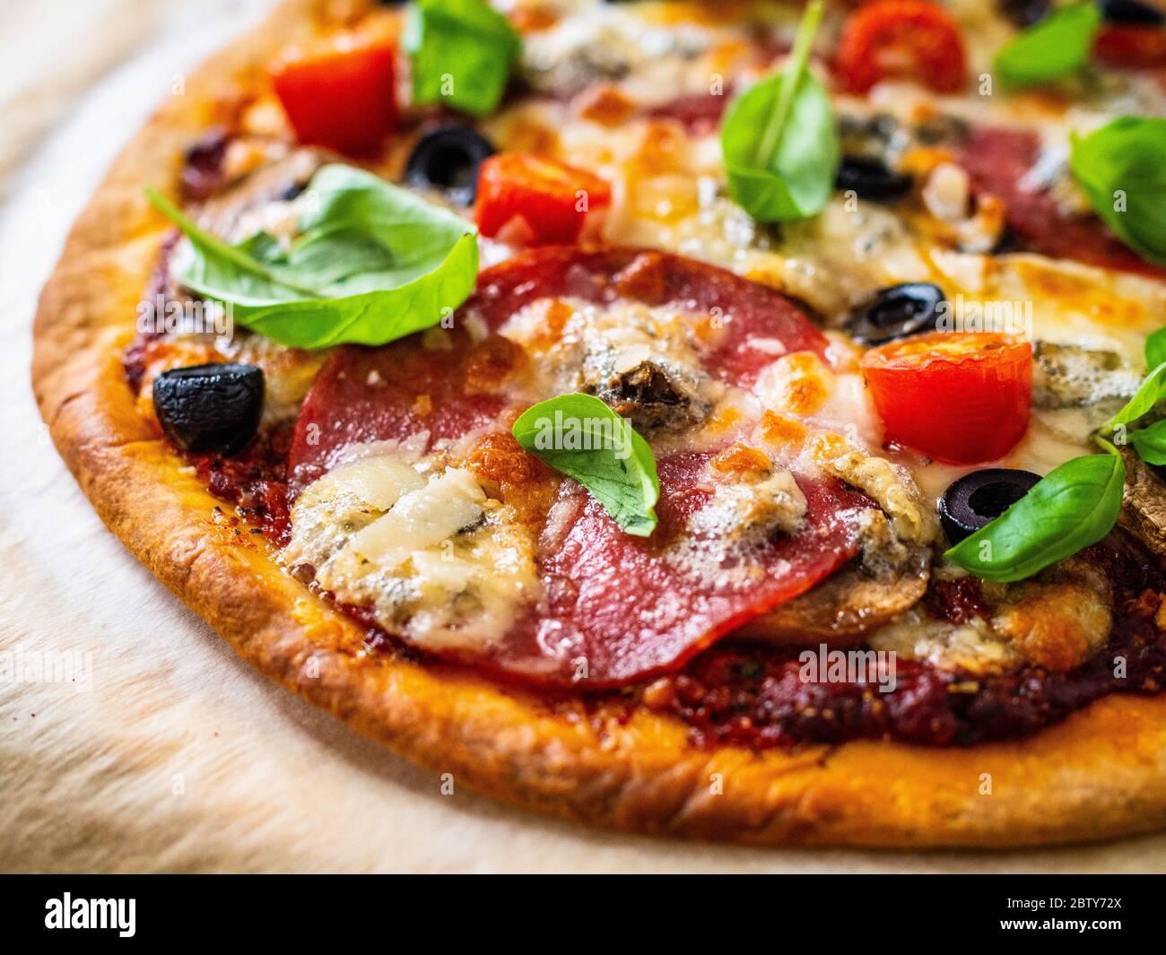 Pizza with salami, champignon,olives and cherry tomatoes Stock Photo