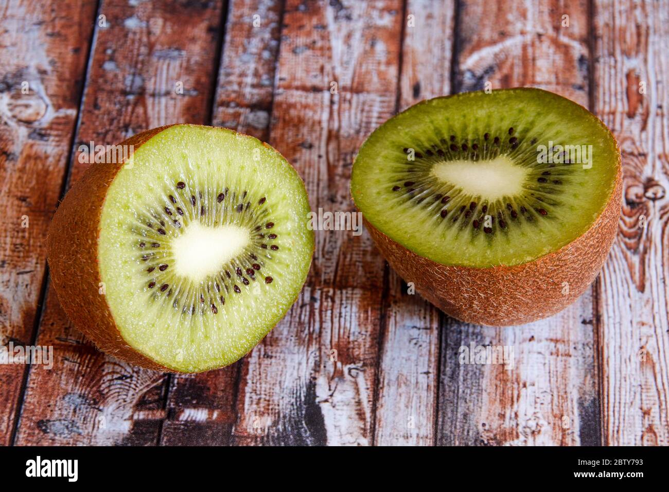 Two halves of kiwi on wood background Stock Photo