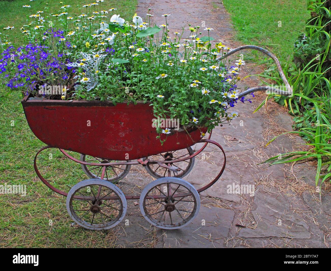 Recycled baby pram, planted in a garden, with flowers Stock Photo