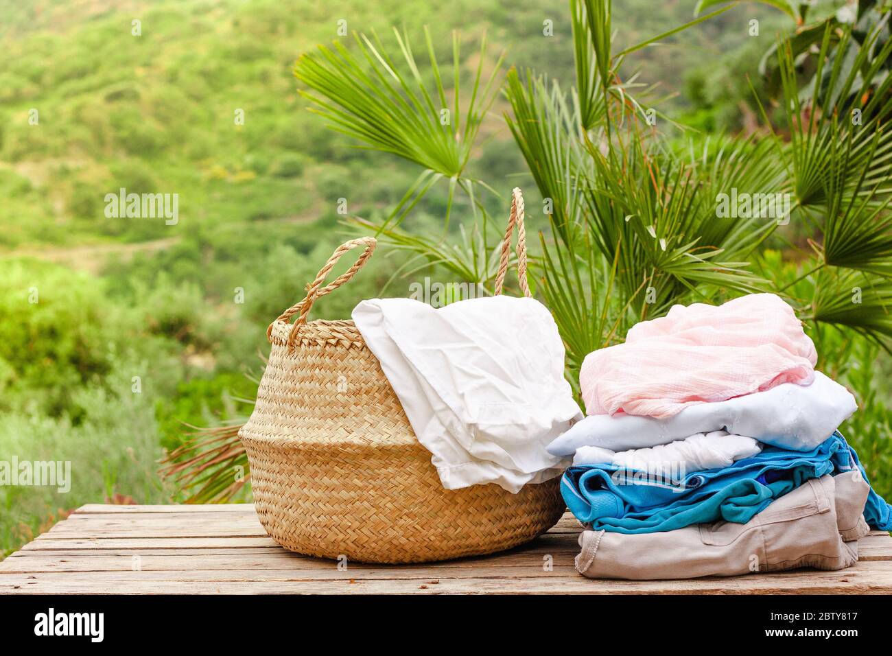 Basket with clean and dry laundry on wooden table on nature background in sunny day Stock Photo Alamy