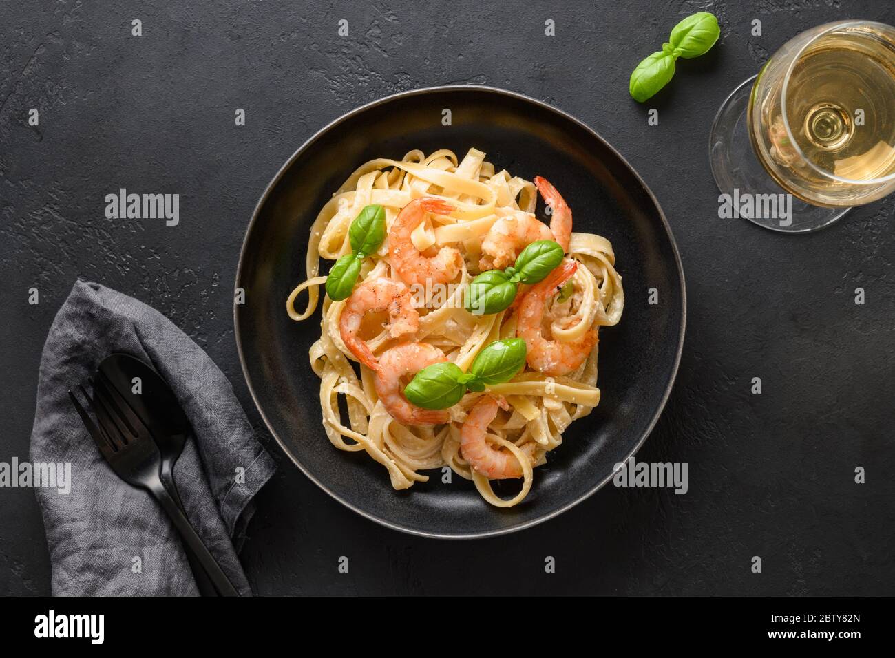 Italian fettuccine with shrimps, seafood served wine glass on black table. View from above. Stock Photo
