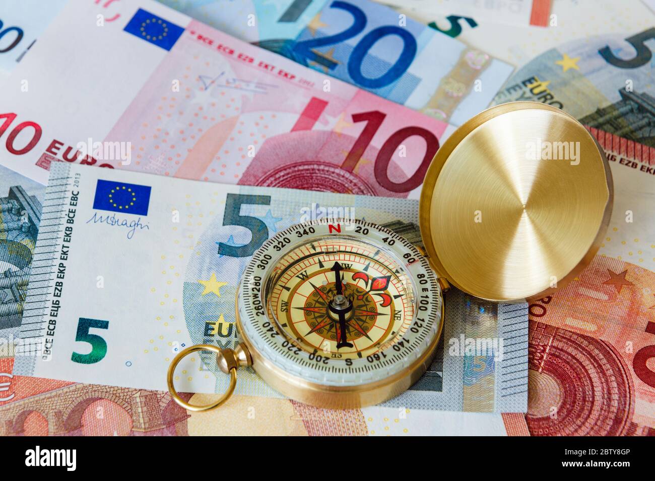 EU money with a brass compass on Euro notes Euros to illustrate future of the Eurozone economy.  Change direction concept. Europe Stock Photo