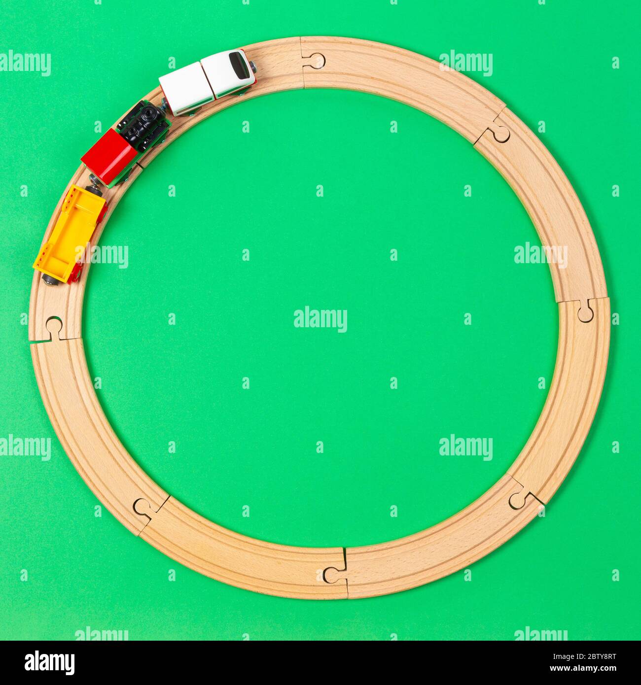 Toy train moves on round wooden railways on light green background. Top