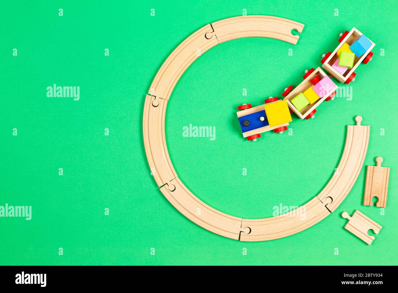 Toy train moves on round wooden railways on light green background. Top