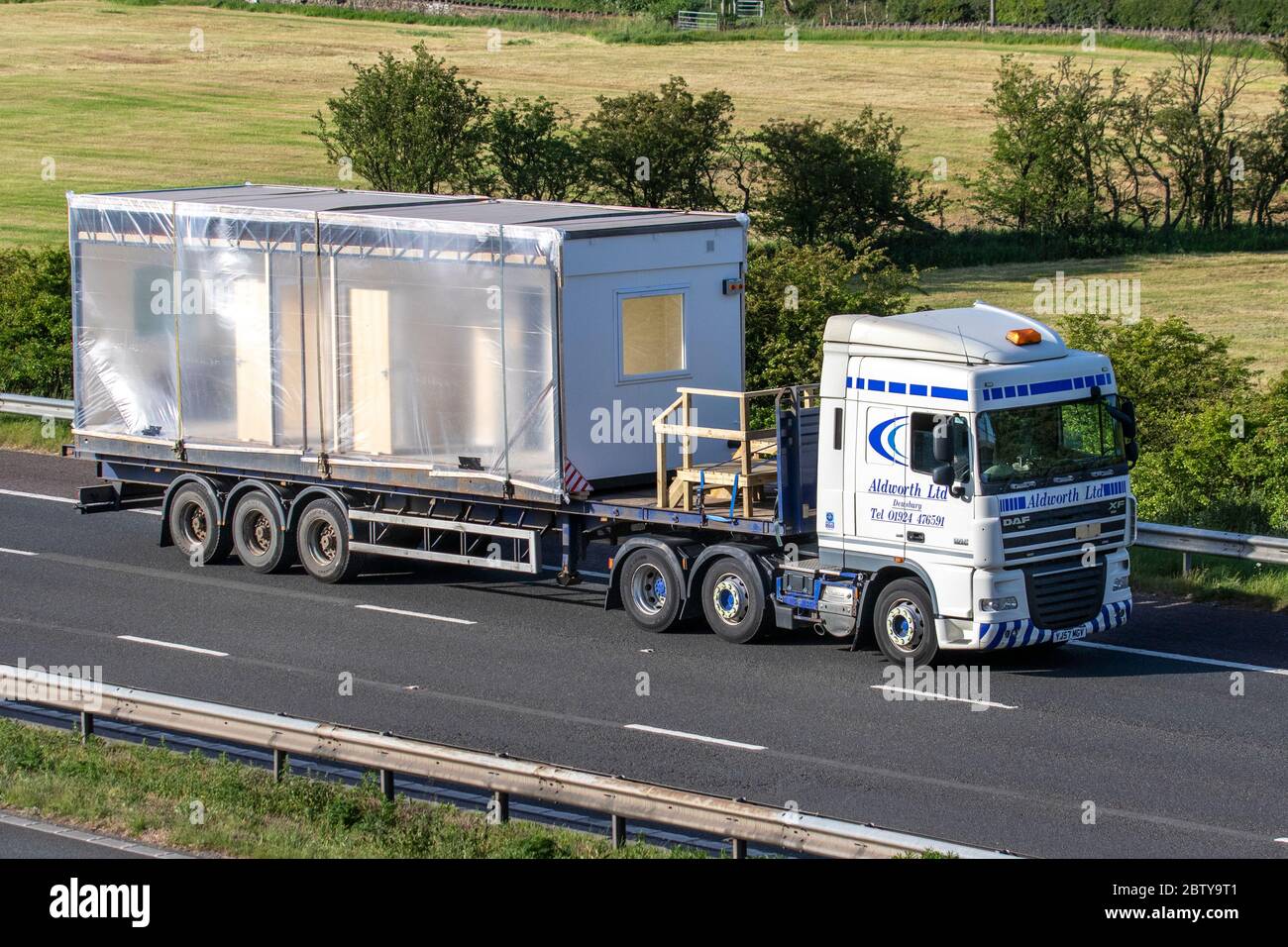 Aldworth Ltd Haulage delivery trucks, HGV lorry, transportation, articulated truck, Steel cabins, containers, modular buildings, flat pack offices, wheeled towable units, cargo carriers, DAF XF vehicle, European commercial transport industry HGV, M6 at Manchester, UK Stock Photo