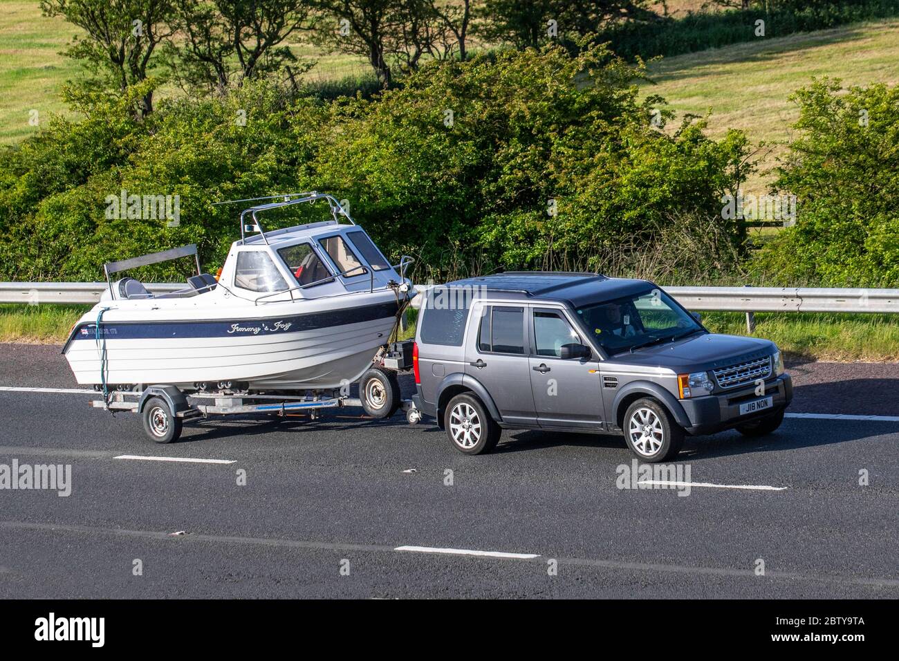 2005 grey Land Rover Discovery 3 TDV6 towing Warrior 175 Jimmy's Joy boat & trailer; Vehicular traffic moving vehicles, cars driving vehicle on UK roads, motors, motoring on the M6 motorway highway Stock Photo