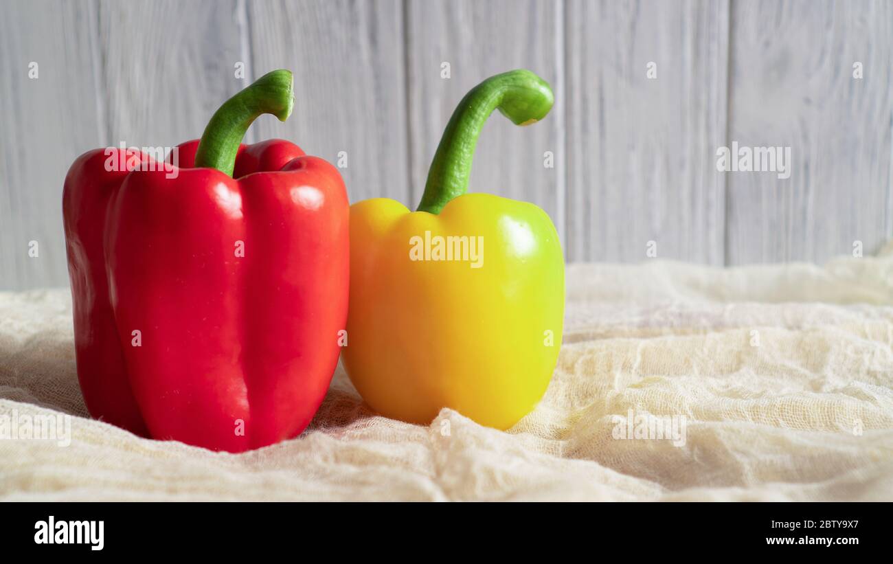 Peppers at home. Soft fabric. Bright vegetables Yellow and red bellpeppers. Light background Appetizing raw ripe peppers Stock Photo