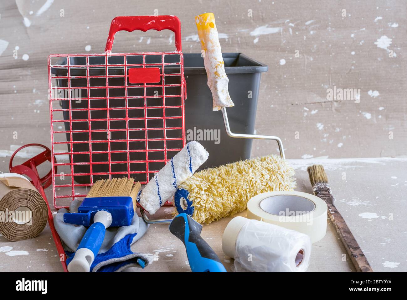 Close up of a bucket with roller grid, paint rollers, paintbrushes and