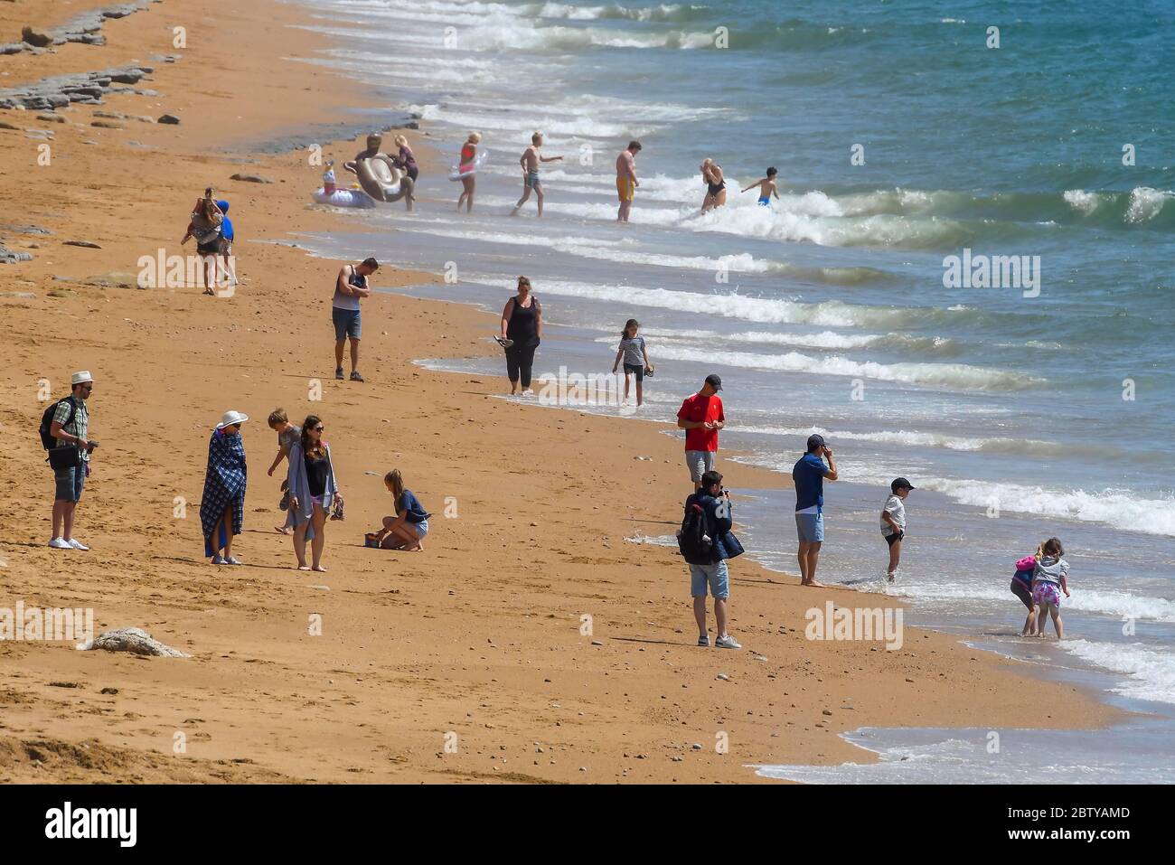 West Bay, Dorset, UK.  28th May 2020.  UK Weather.  Families and sunbathers bask in the scorching hot sunshine at the seaside resort of West Bay in Dorset.  Picture Credit: Graham Hunt/Alamy Live News Stock Photo