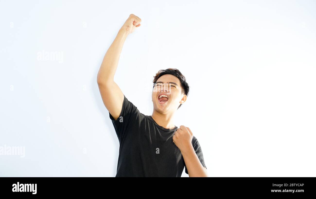 Portrait of a satisfied young asian man celebrating success isolated over white background Stock Photo