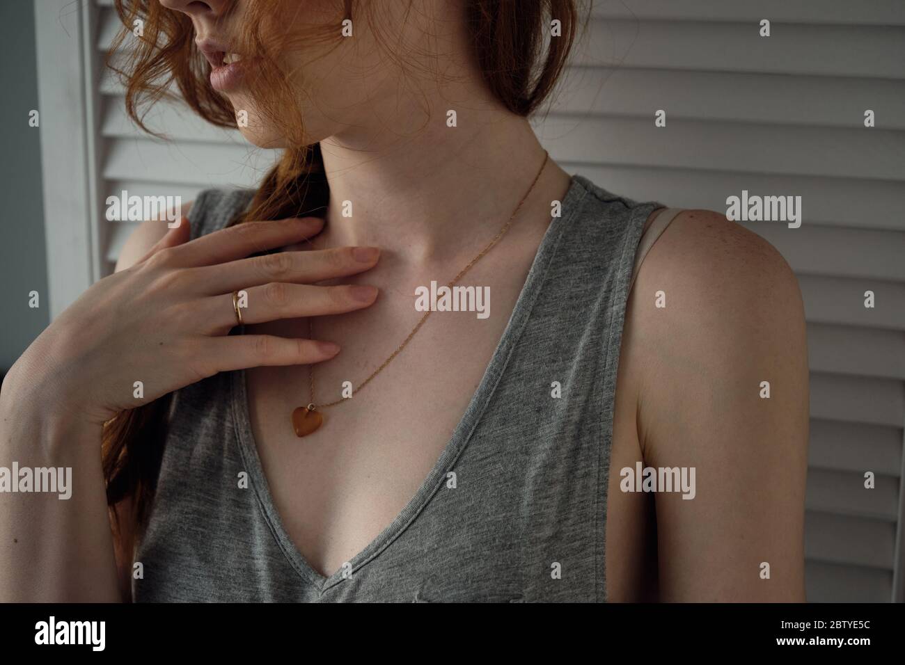 Body parts. Close shot of the hands of a red-haired girl on the collarbone, lips, shoulders, wavy hair Stock Photo