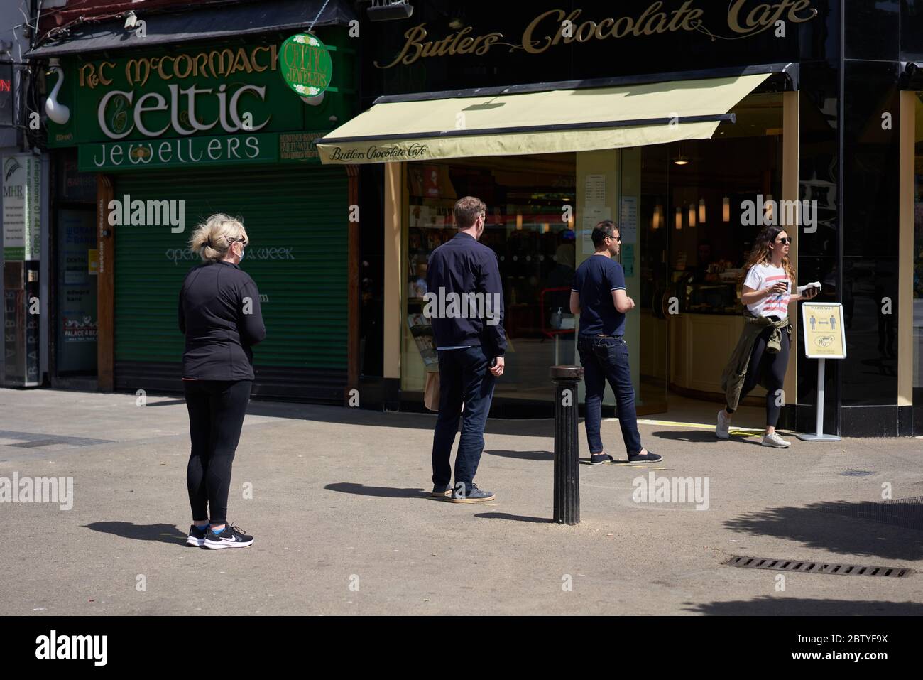 People social distancing while queuing for coffee in Dublin city, during the global coronavirus pandemic. Stock Photo