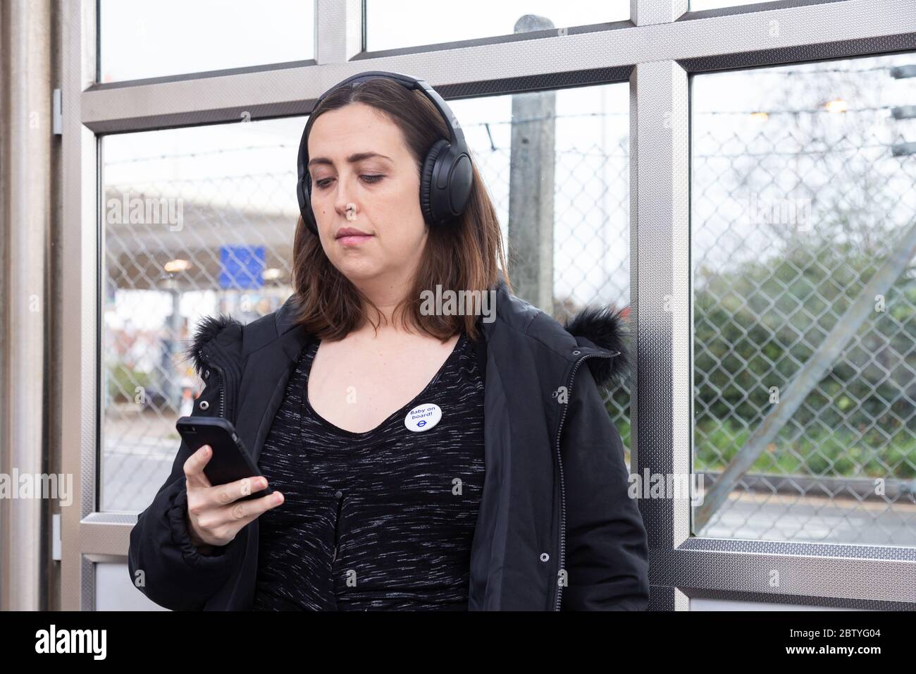 Pregnant passenger waits for her train in a station shelter at New Cross Gate Stock Photo