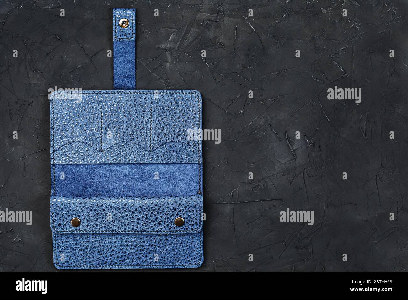 Blue leather wallet on a black textured background. Stock Photo