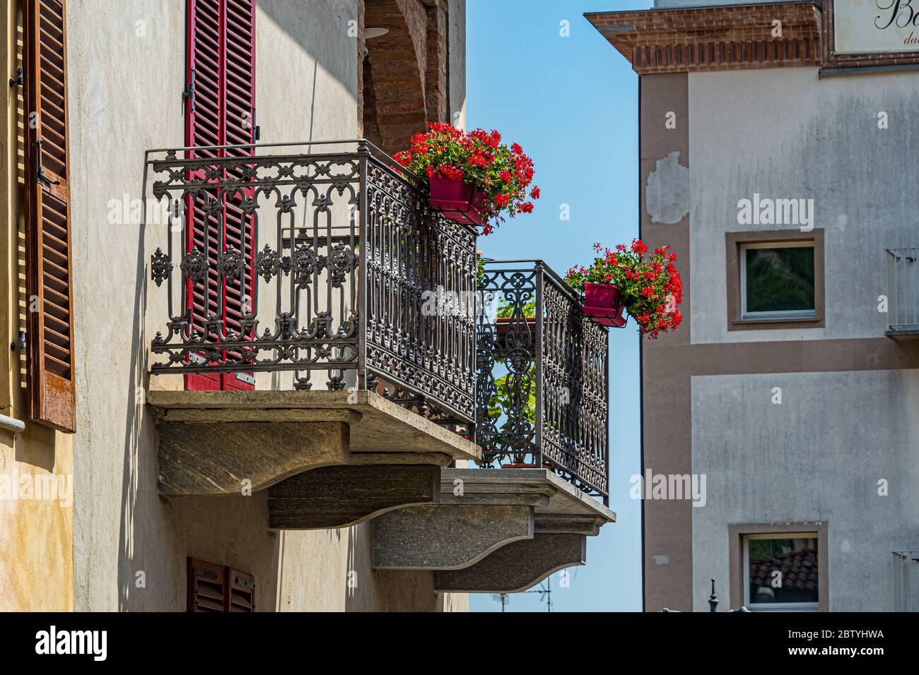 Beautiful old metal balconies with flowers at the front - City of Barolo, Italy, Piedmont Stock Photo