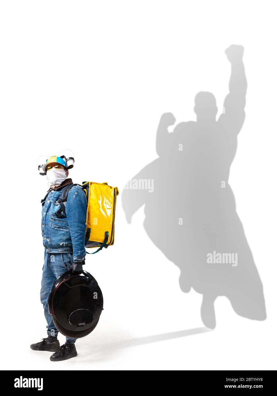 Superhero in shadow of ordinary people - modern superhero's concept, respect and admiration. Deliveryman keeping work despite infection risk during pandemic, setting good example. Inspiring others. Stock Photo