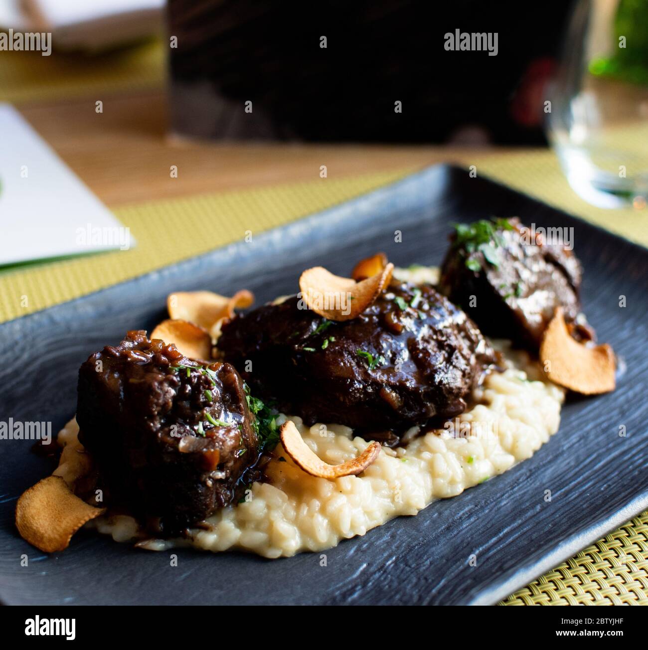 Ossobuco or osso buco is a specialty of Lombard cuisine of cross-cut veal shanks braised with vegetables, white wine and broth. Served with either ris Stock Photo