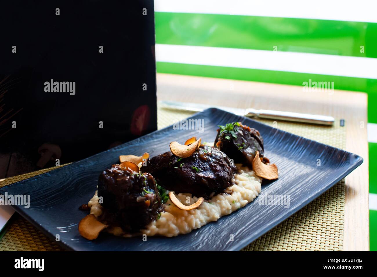 Ossobuco or osso buco is a specialty of Lombard cuisine of cross-cut veal shanks braised with vegetables, white wine and broth. Served with either ris Stock Photo