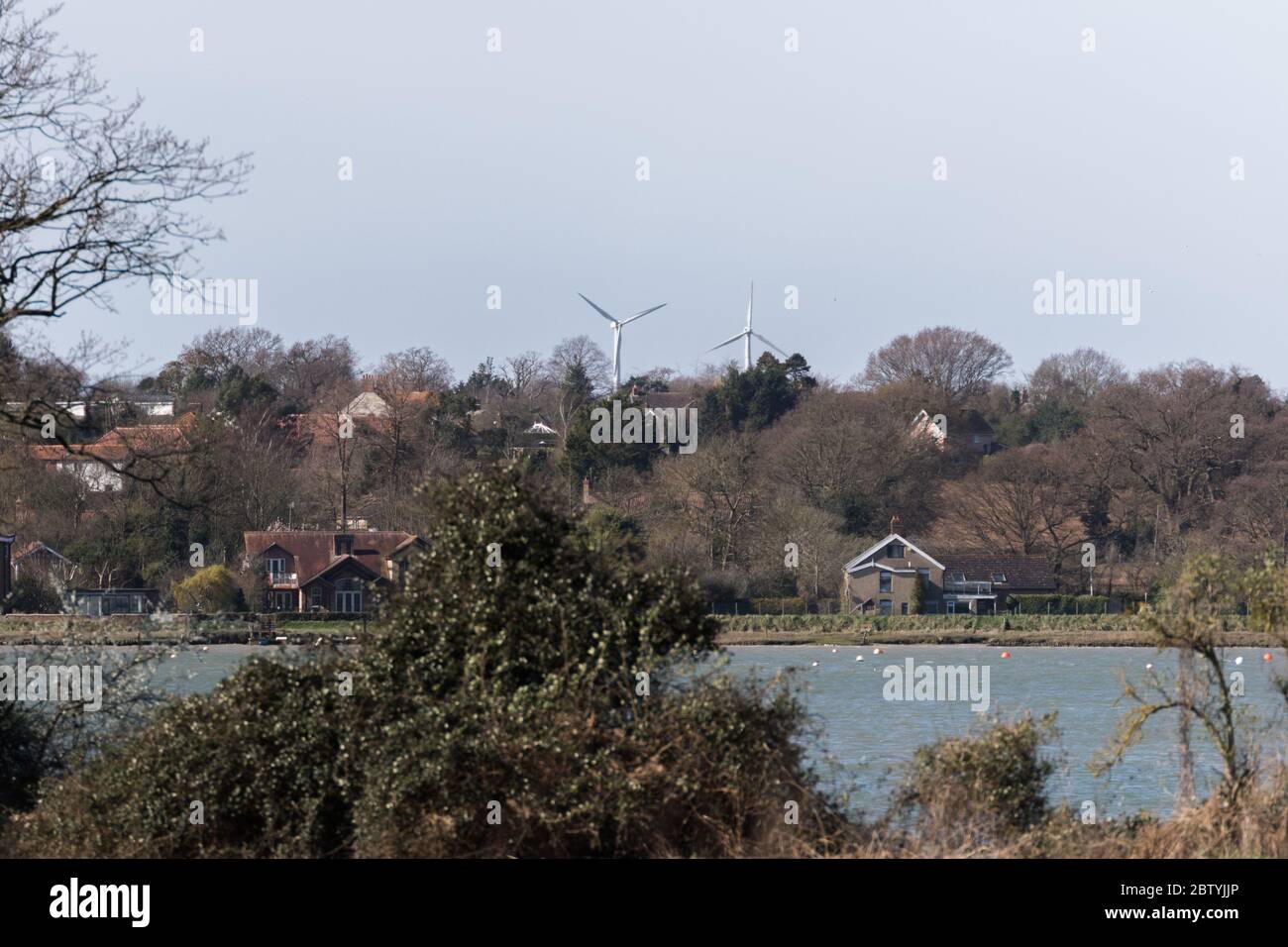 A rural countryside scene with a pair of wind turbines in the distance