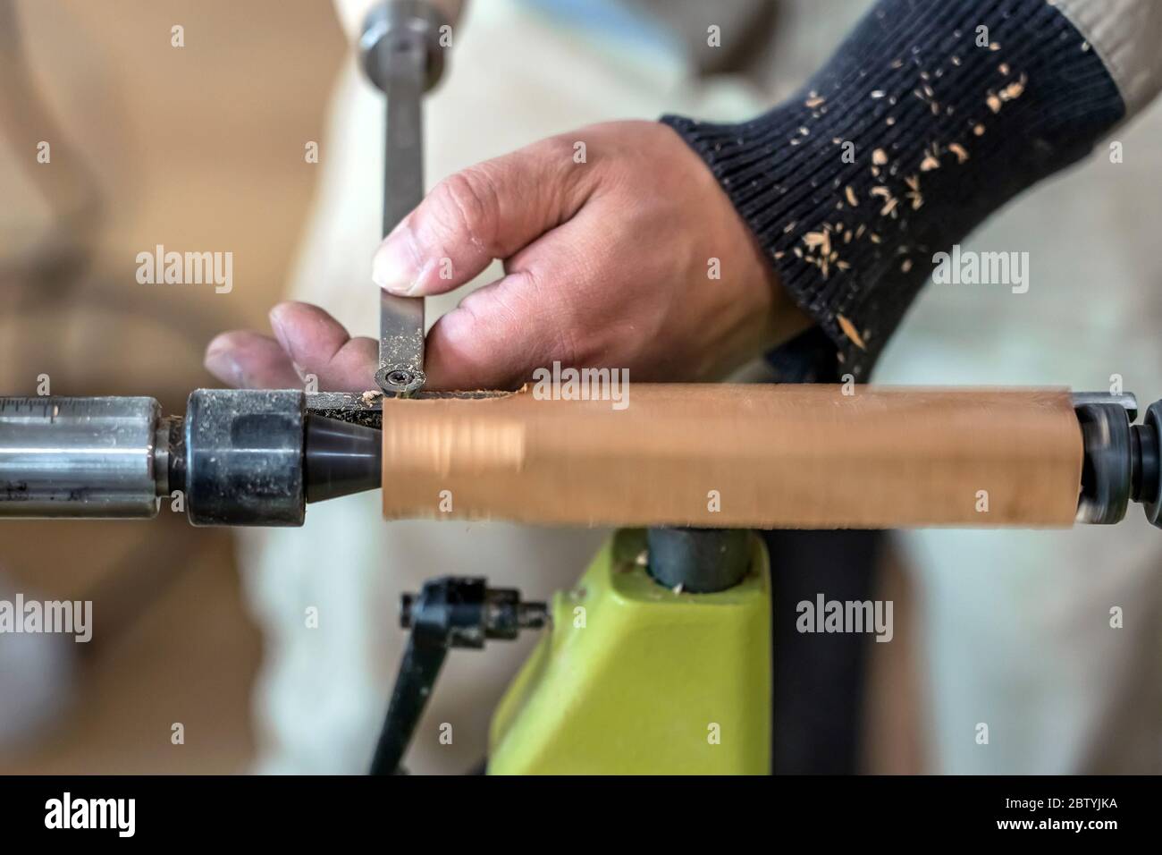 Carpenter man is carving the wooden stick. Spinning wood wheel machine