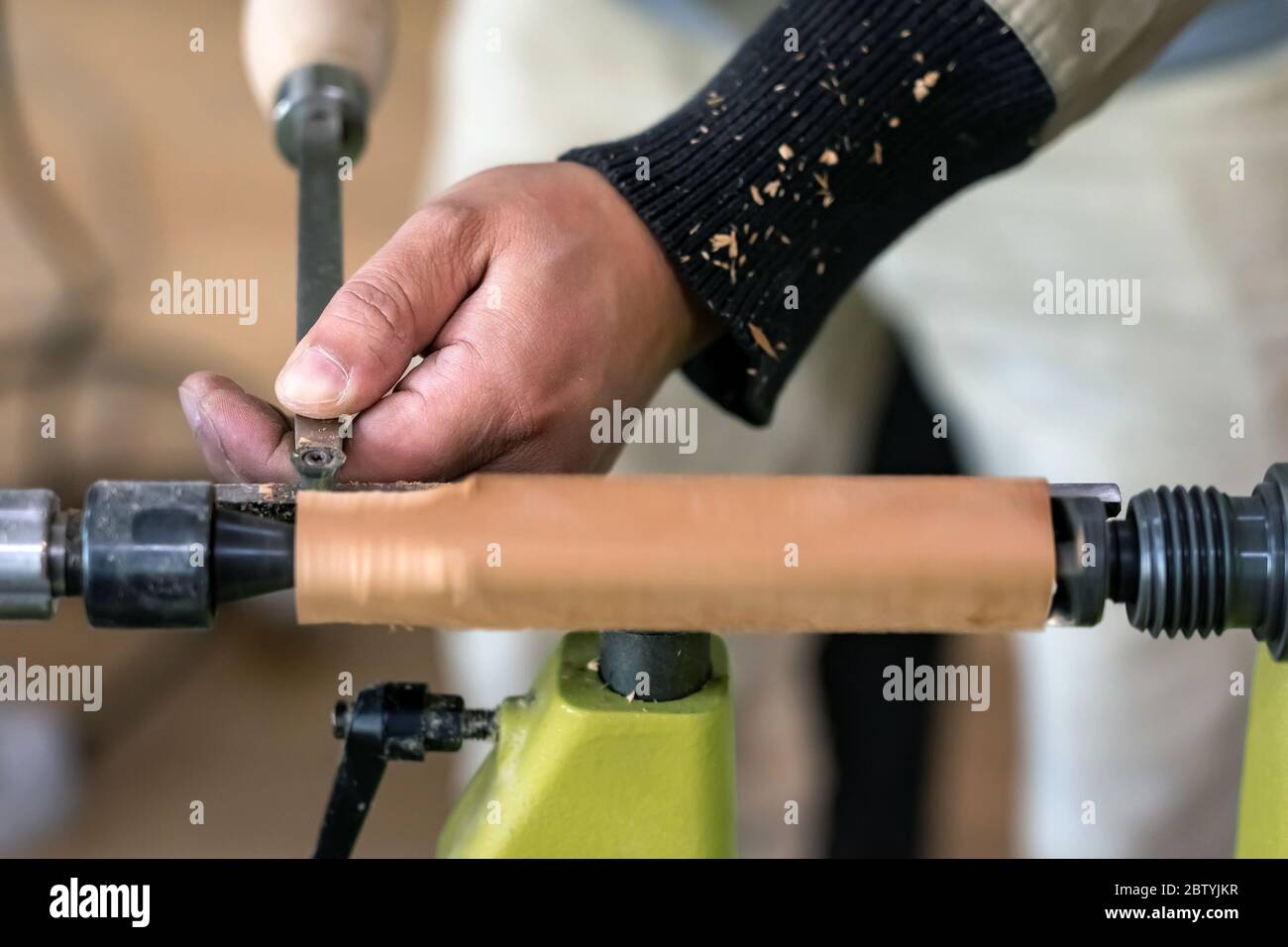 Carpenter man is carving the wooden stick. Spinning wood wheel machine