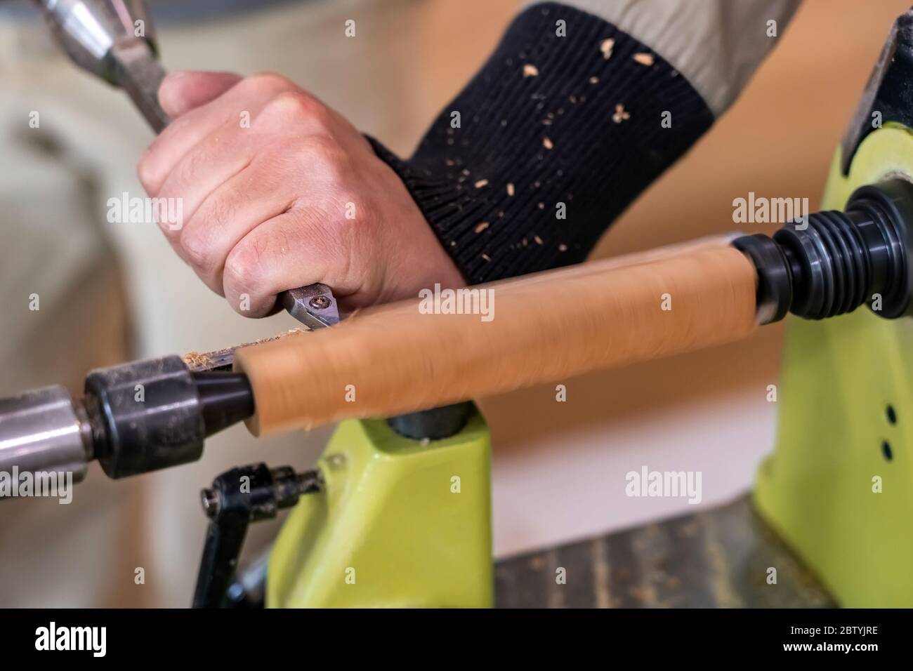 Carpenter man is carving the wooden stick. Spinning wood wheel machine