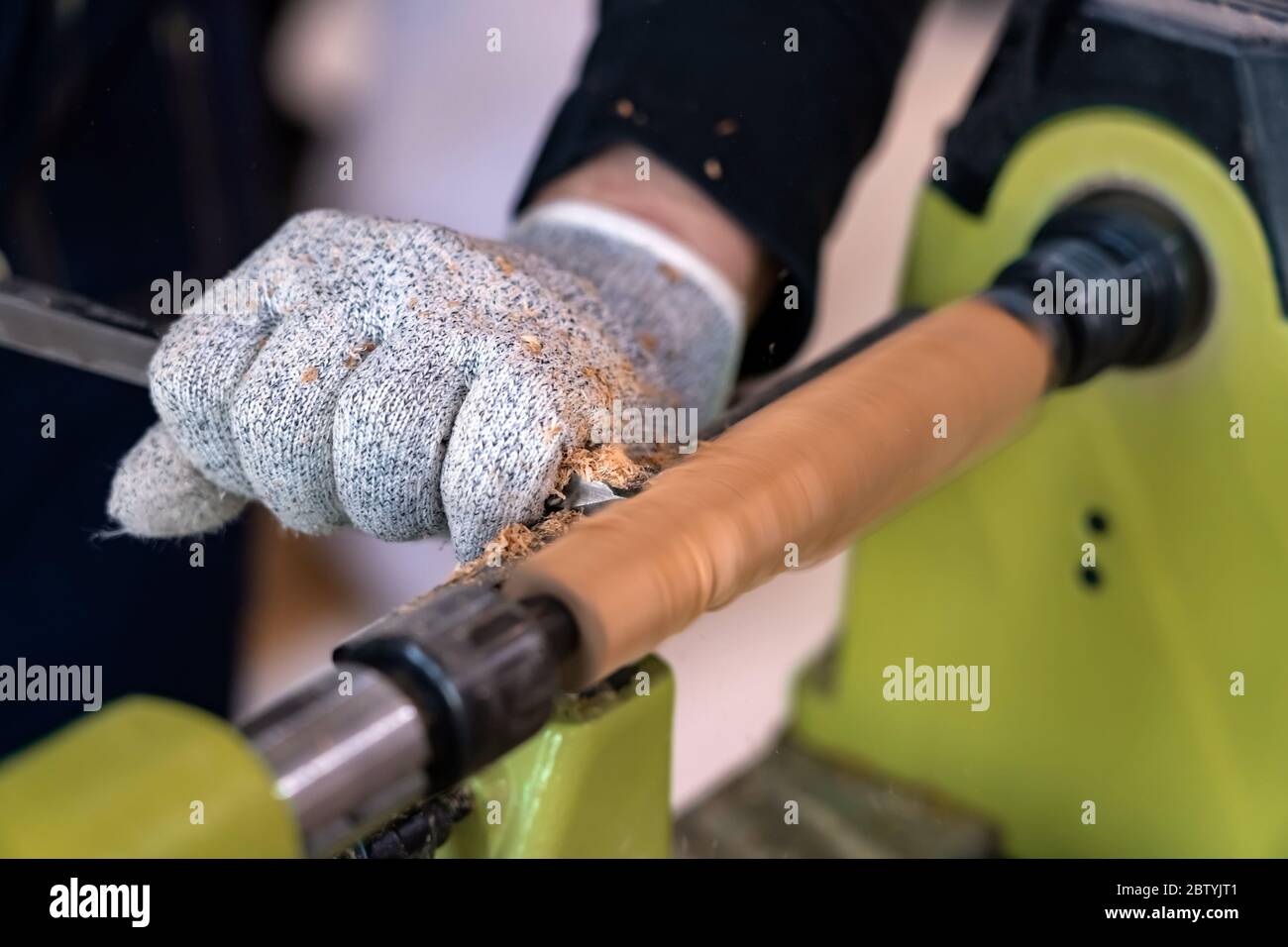 Carpenter man is carving the wooden stick. Spinning wood wheel machine