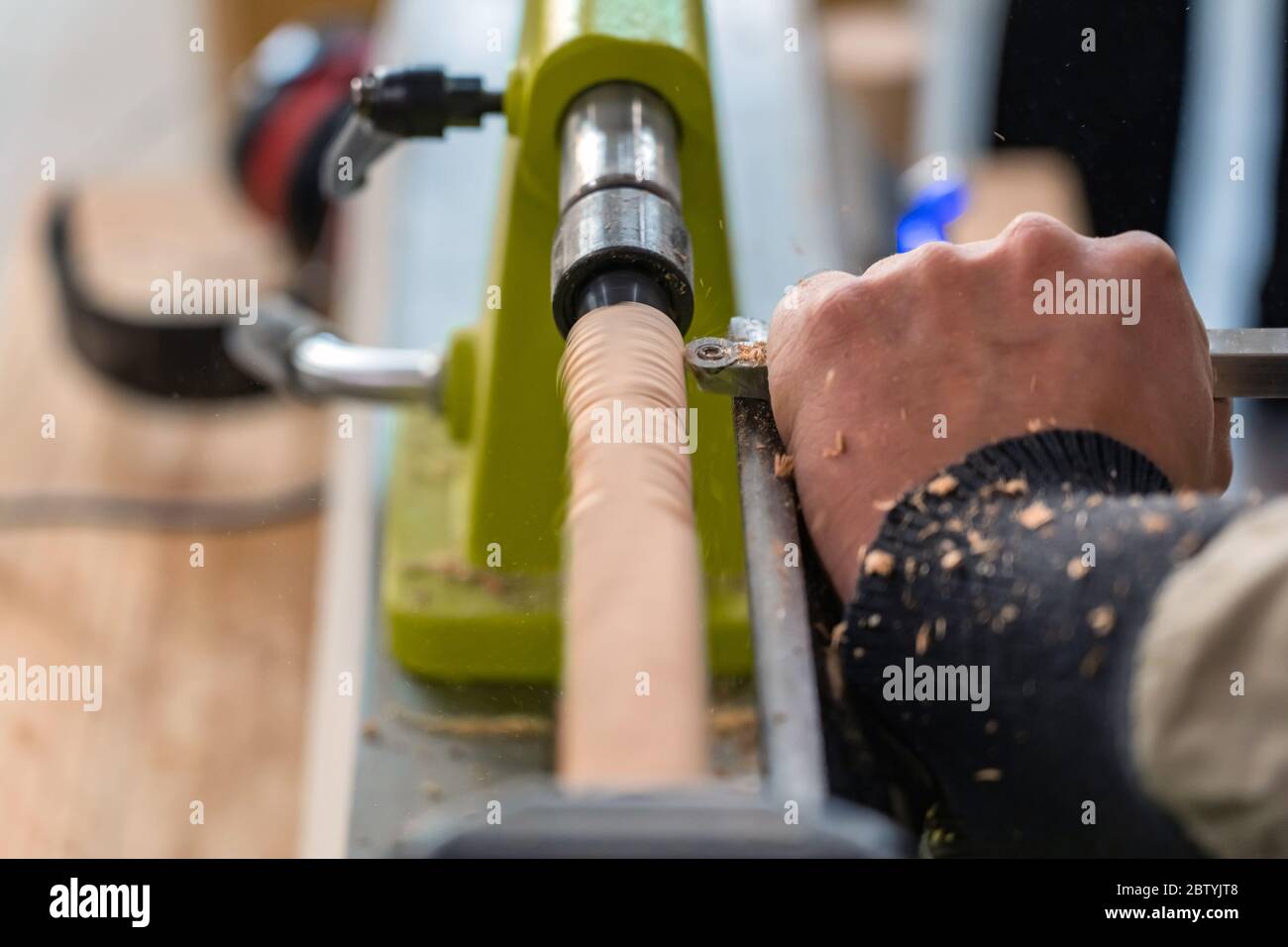 Carpenter man is carving the wooden stick. Spinning wood wheel machine