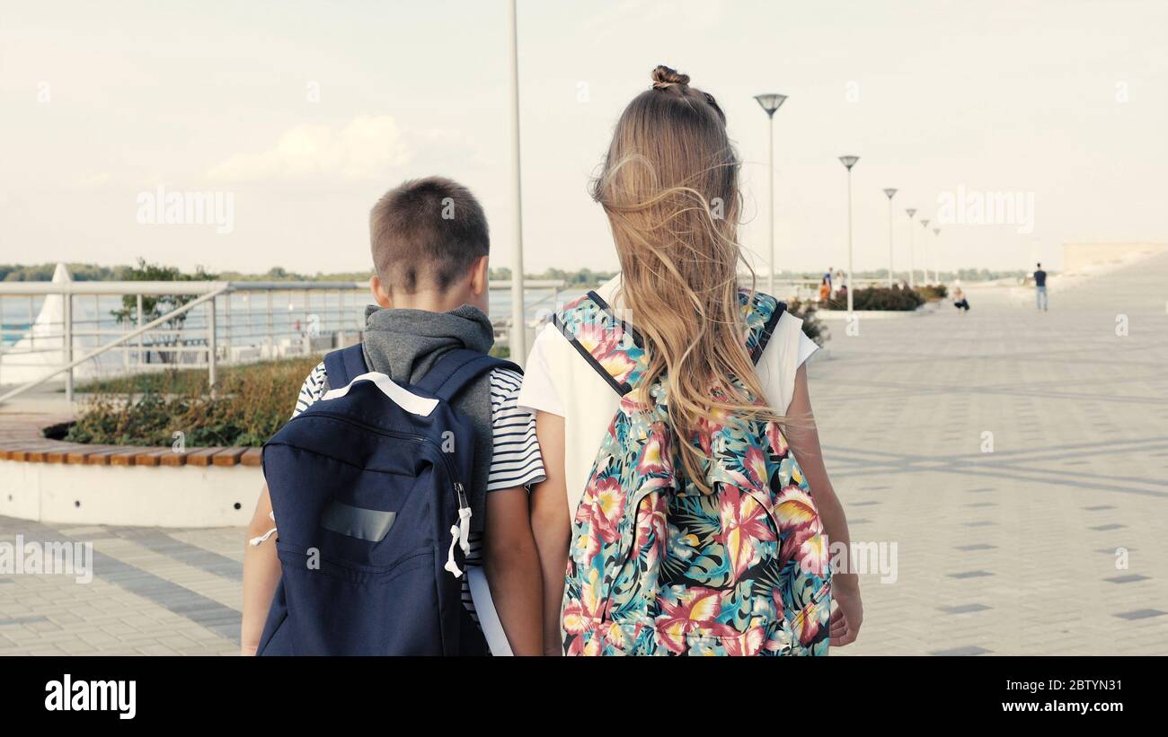 A boy and a girl walking with backpacks. Stock Photo