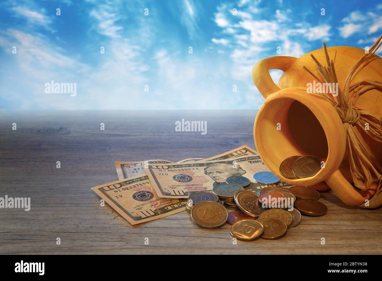Money and coins of different countries scattered from the jug. Stock Photo