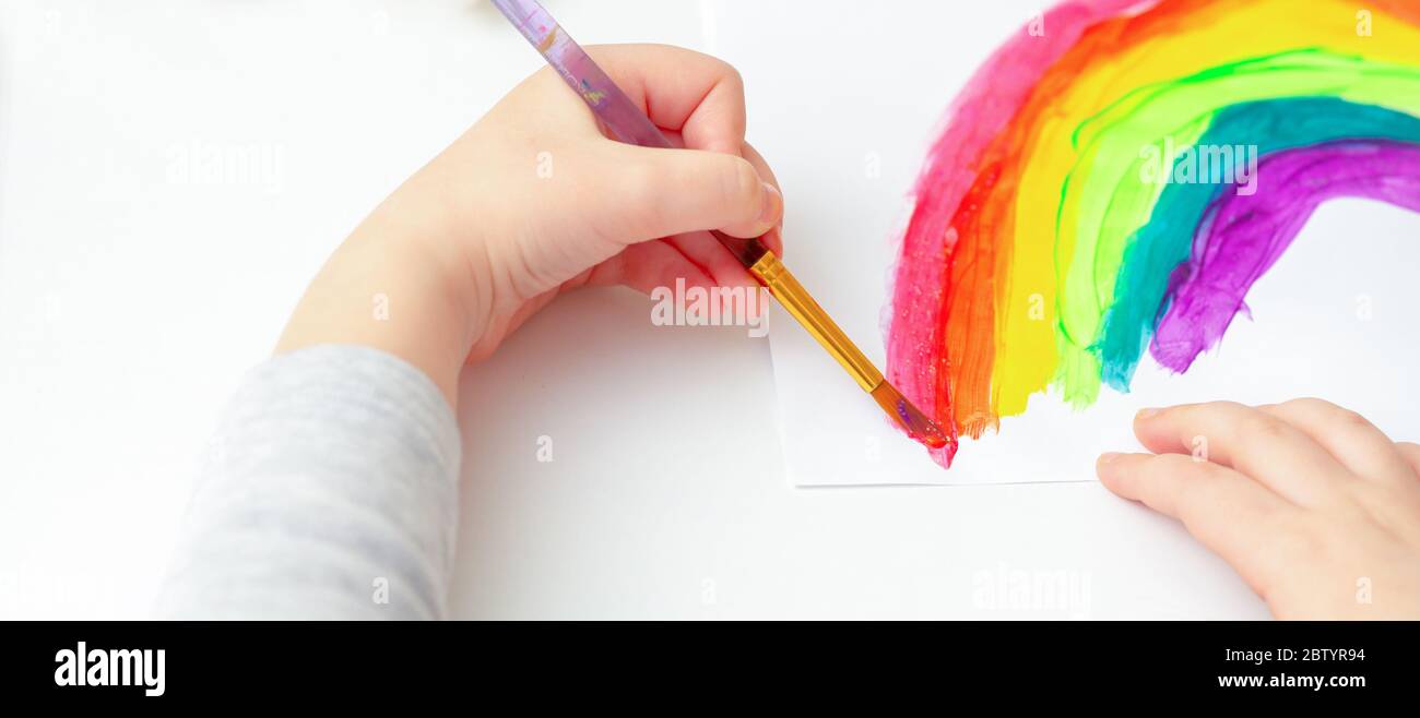 Painted rainbow by the hands of a child with watercolors on a white sheet of paper. Stock Photo
