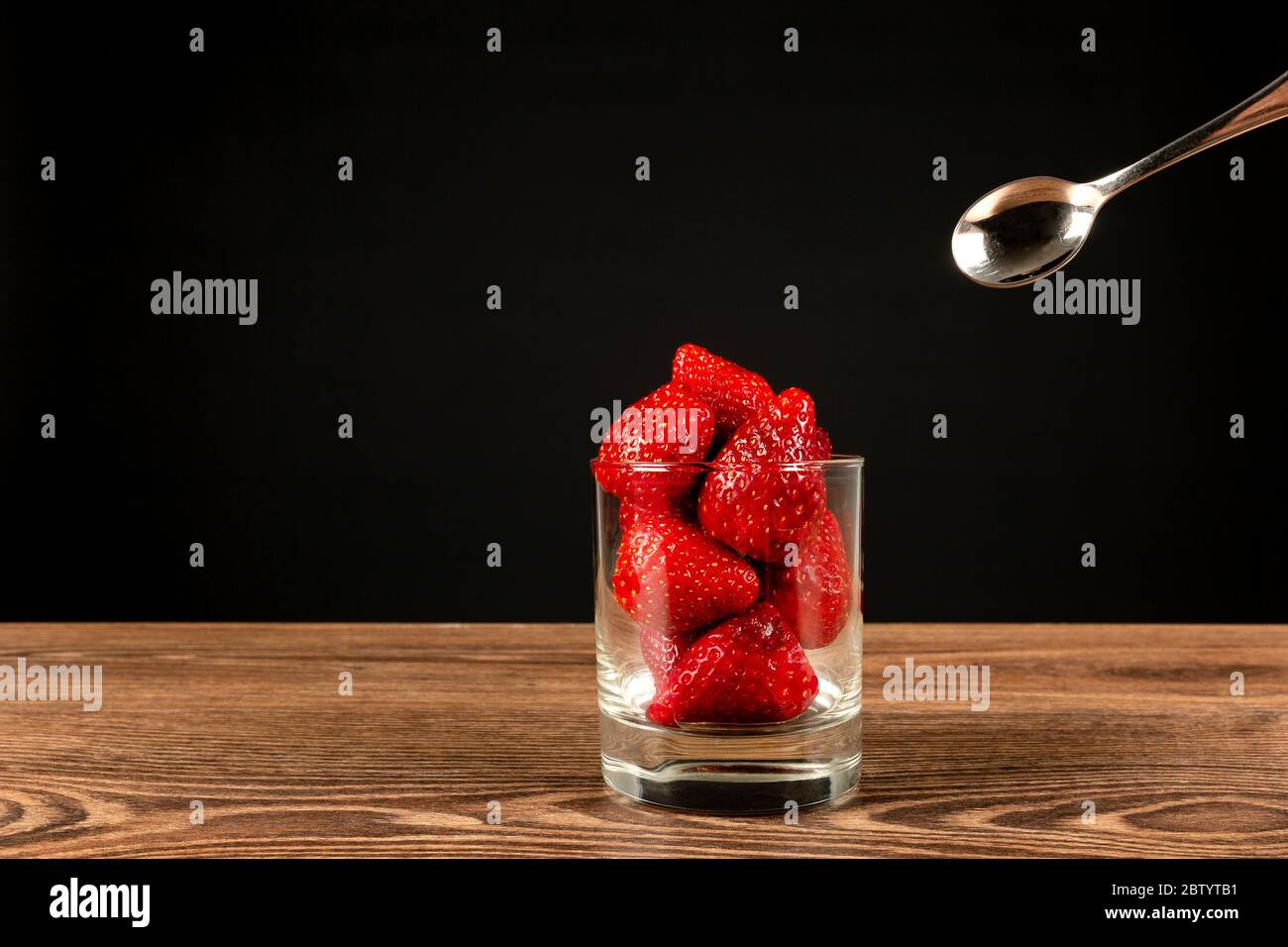 Strawberries in a glass with a spoon on a dark background Stock Photo ...