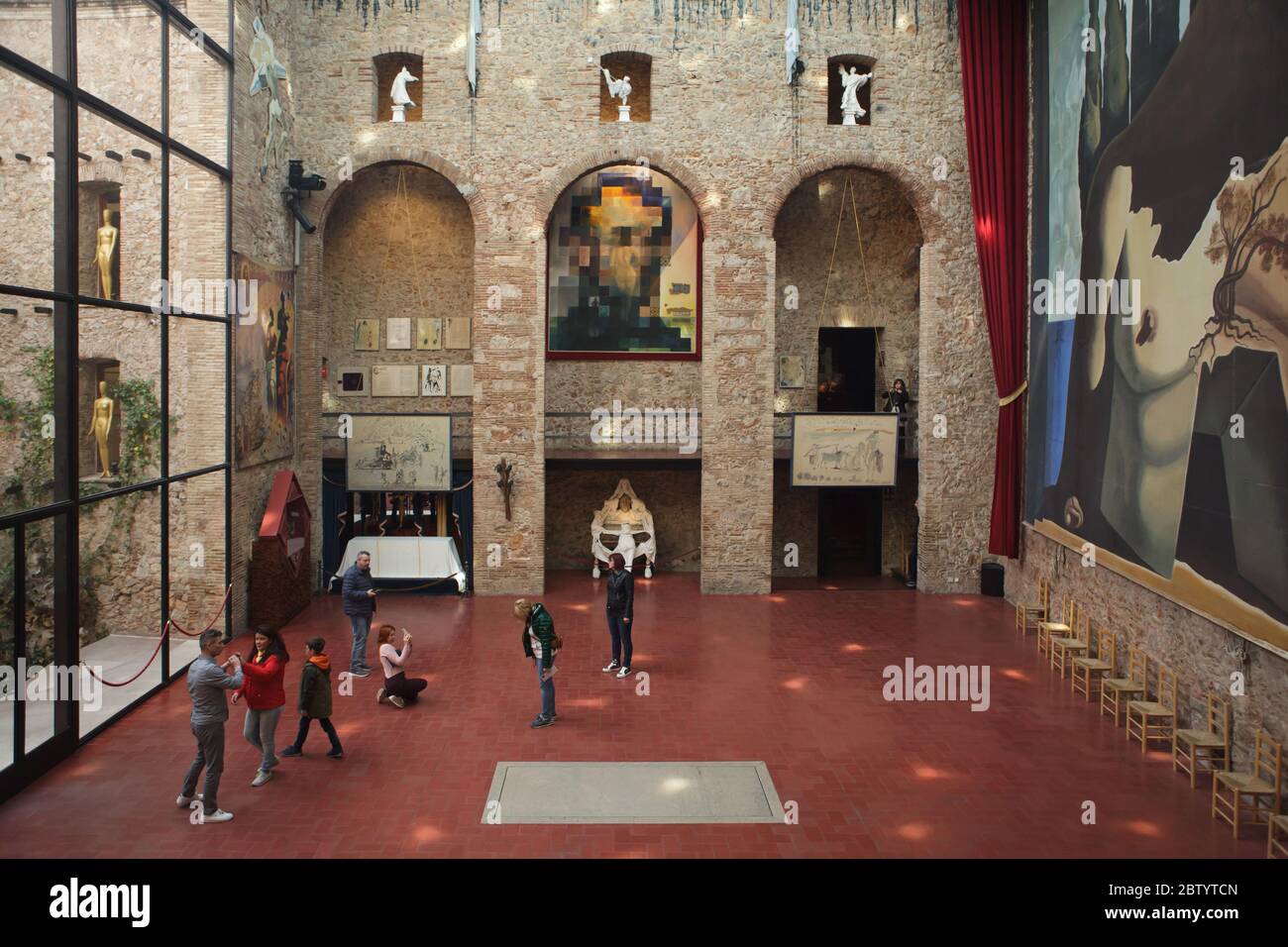 Visitors stay next to the unmarked grave of Spanish surrealist painter Salvador Dalí in the main hall of the Salvador Dalí Theatre and Museum in Figueres, Catalonia, Spain. The painting by Salvador Dalí entitled 'Lincoln in Dalivision' is seen in the background, while the huge backdrop also designed by Salvador Dalí for the ballet Labyrinth (1941) is seen in the right. Stock Photo