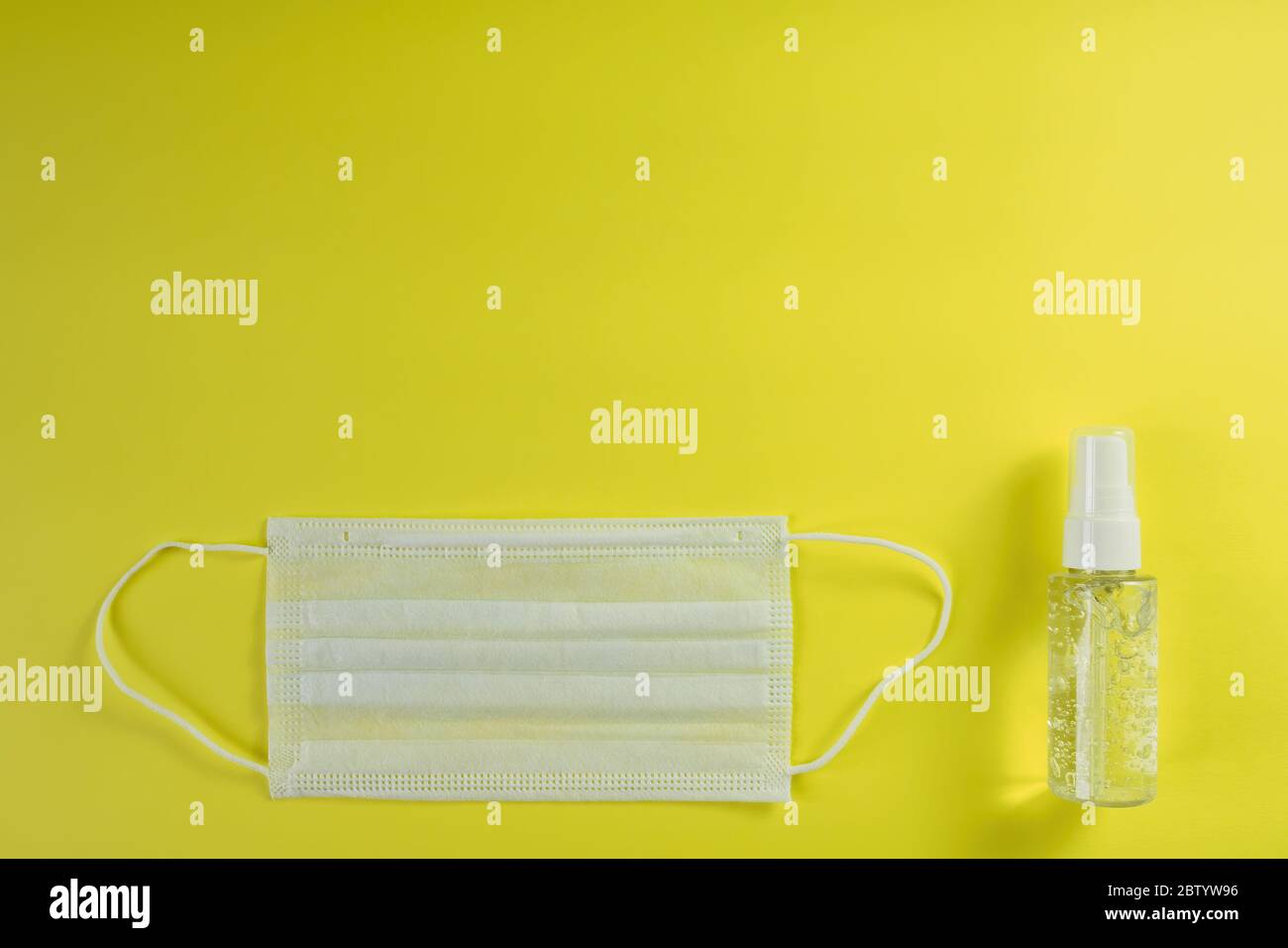 White medical mask and alcohol gel on yellow background. Surgical mask and antibacterial soap sanitizer. Hygiene concept for prevent the spread corona Stock Photo