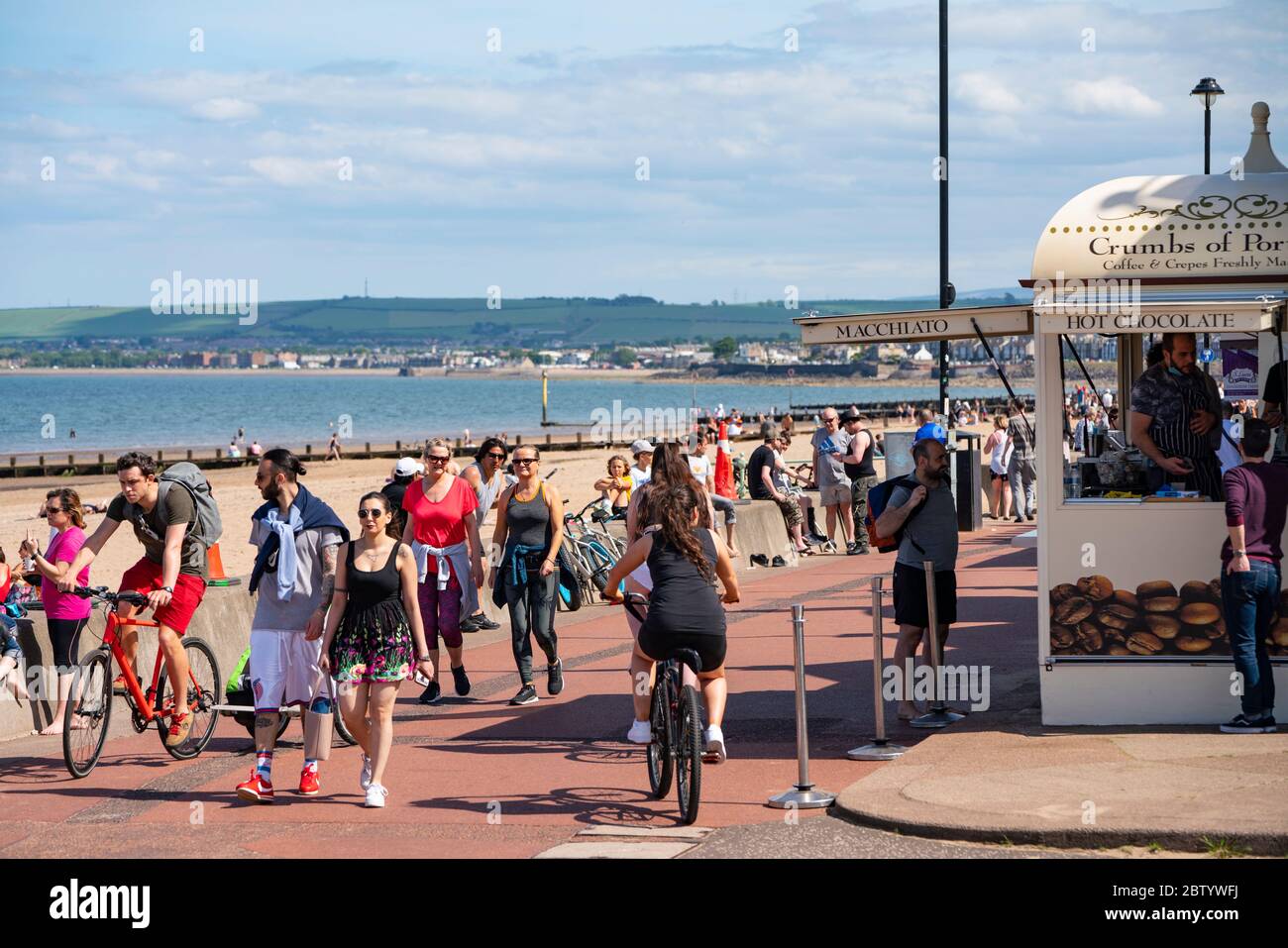 Portobello, Scotland, UK. 28 May 2020. Warm sunny weather with temperatures reaching 24C brought many people to the beach and promenade at Portobello, Edinburgh. The public seem to sense that the lockdown is being relaxed are are taking advantage of the good weather to sunbathe and enjoy the many cafes that are now offering takeaway snacks. Iain Masterton/Alamy Live News Stock Photo